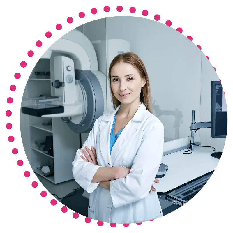 A female medical professional in a white lab coat stands with crossed arms in a medical imaging room, featuring advanced equipment.