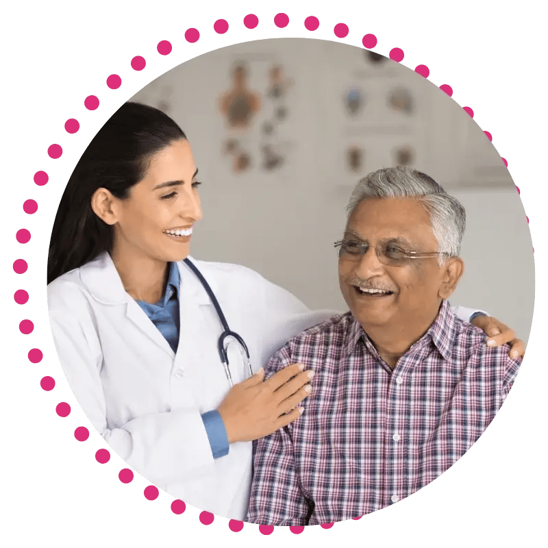 A smiling doctor in a white coat with a stethoscope comforts an elderly man