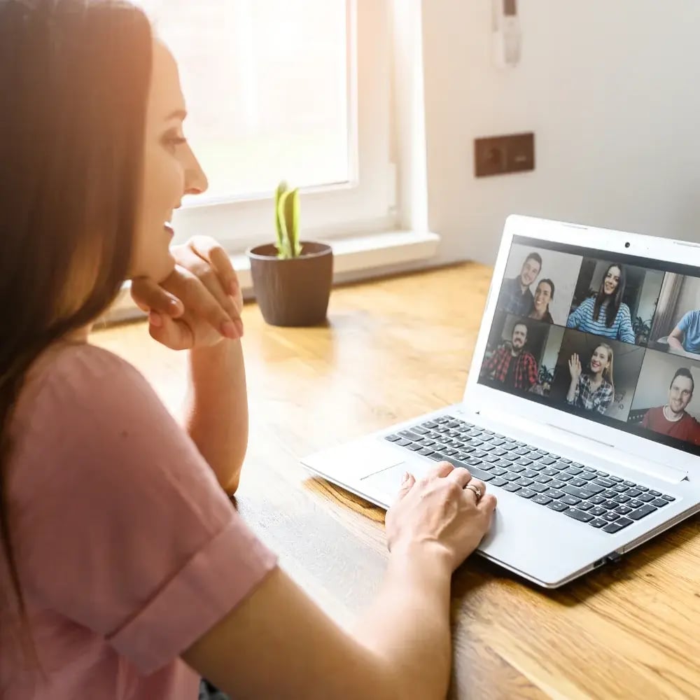 A woman engaging in conversation in a video meeting on a laptop.