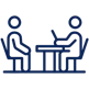 Blue icon of two individuals seated at a table.
