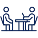 Blue icon of two individuals seated at a table.