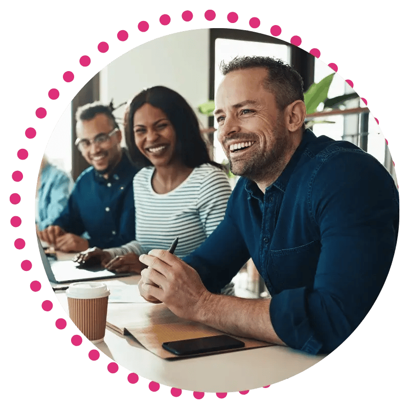 A group of diverse individuals seated at a table, each using laptops and engaged in discussion or collaboration