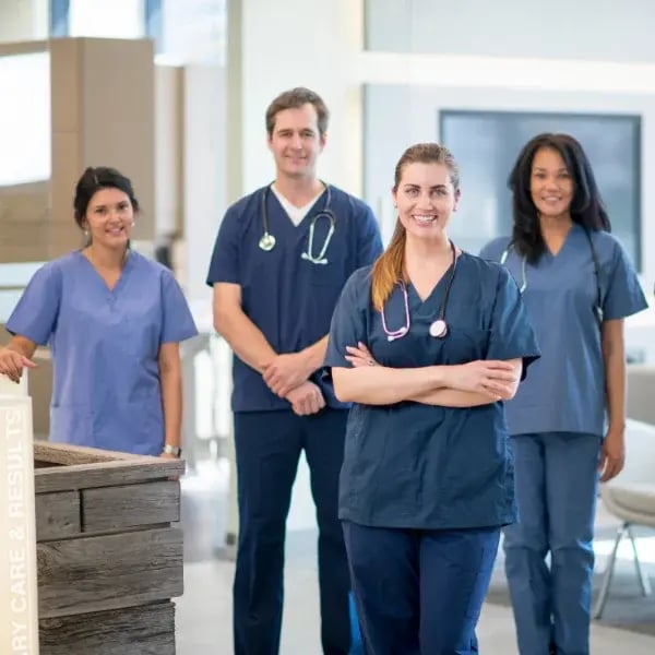 A group of three doctors and one nurse smiling to the camera in a hospital reception