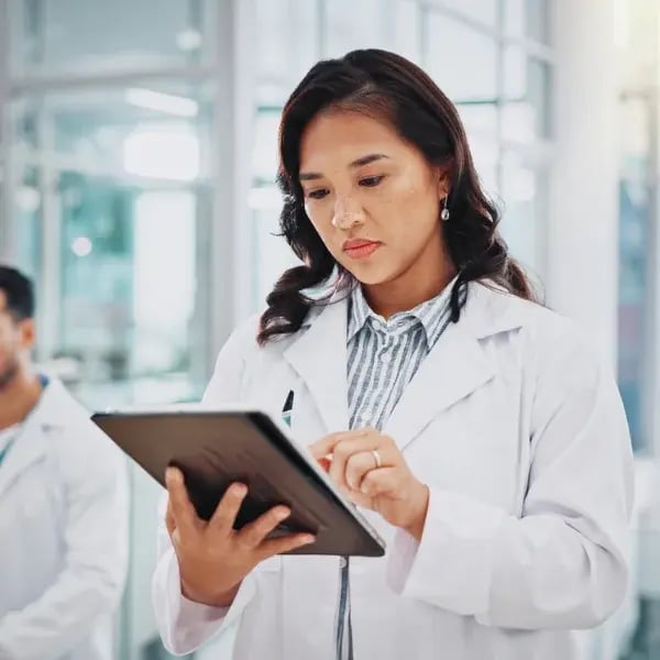 A doctor in a white coat checking a tablet