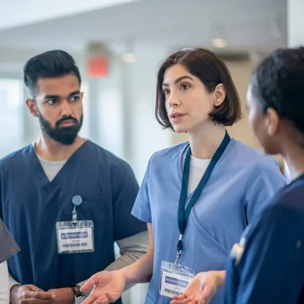 Three blue shirt doctors discussing in a hospital