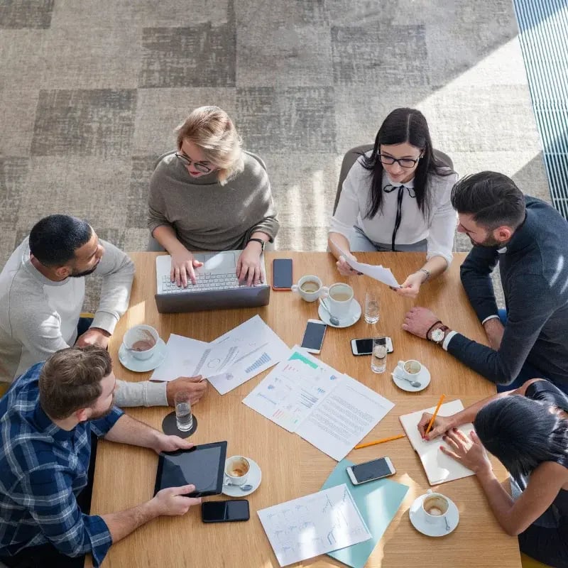 Aerial view of business people engaged in a meeting at a table, working on laptops and sharing ideas