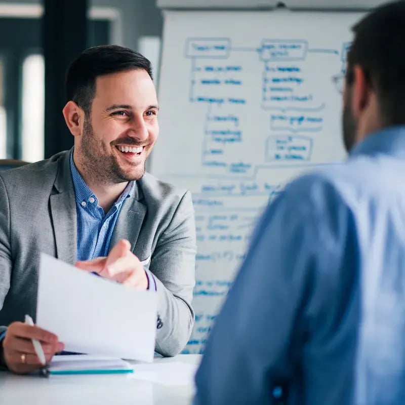 A man is conversing with another man in a professional office setting.