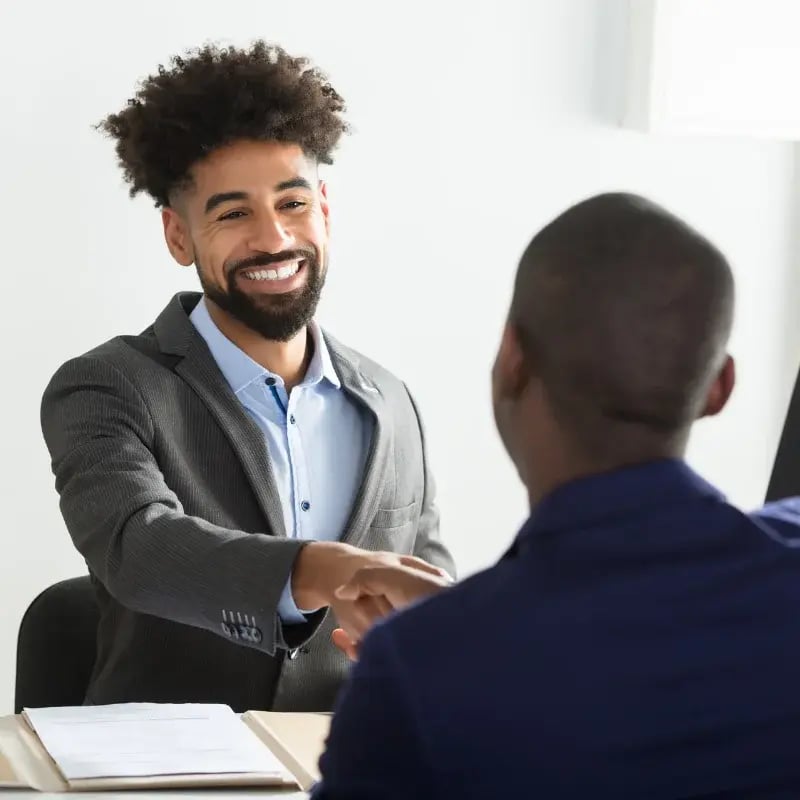 A man in a suit shakes hands with another man, symbolizing a professional agreement or greeting