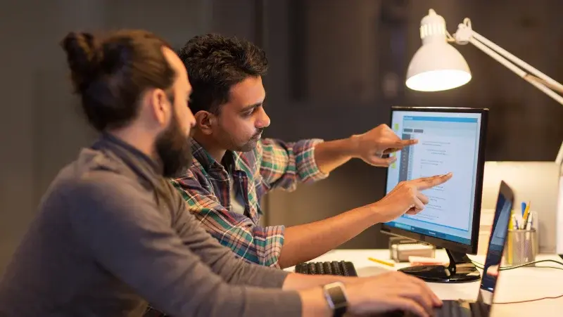 Two men looking at a monitor's code in an office