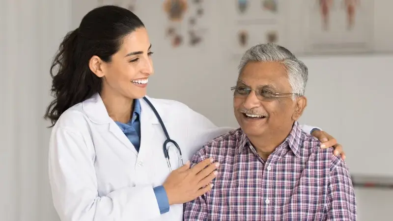 A female doctor with an patient both smiling in a consultation room