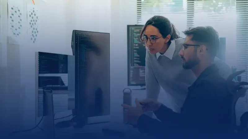 Two colleagues checking a code on a screen
