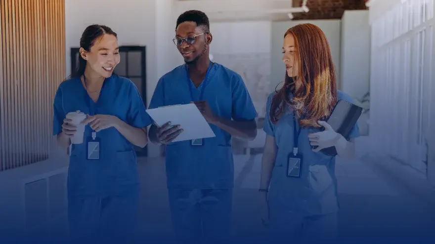 3 doctors discussing information in a tablet while walking in a hospital aisle