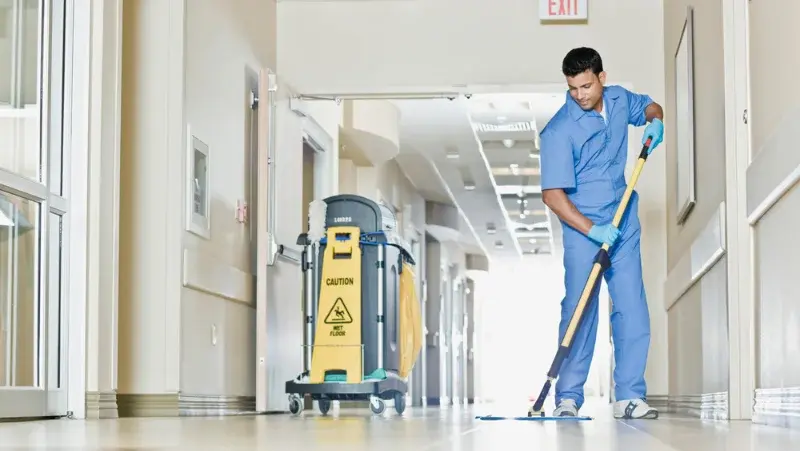 A man cleaning the floor in a hospital corridor
